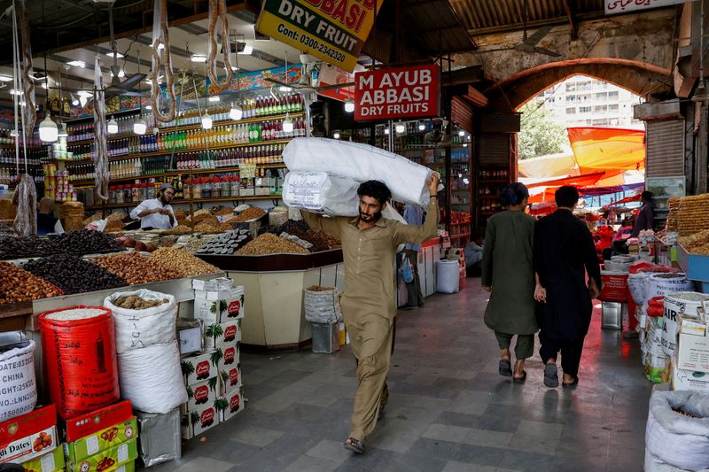 &copy; Reuters. FILE PHOTO: A man walks with sacks of supplies on his shoulder to deliver to a nearby shop at a market in Karachi, Pakistan June 11, 2024. REUTERS/Akhtar Soomro/File Photo