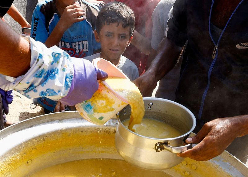 &copy; Reuters. FILE PHOTO: A child looks on as Palestinians gather to receive food cooked by a charity kitchen, amid the Israel-Hamas conflict, in Khan Younis in the southern Gaza Strip, October 16, 2024. REUTERS/Mohammed Salem/File Photo