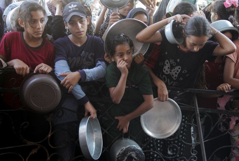 © Reuters. FILE PHOTO: Palestinians wait to receive food cooked by a charity kitchen, amid a hunger crisis as conflict between Israel and Hamas continues, in the northern Gaza Strip August 14, 2024. REUTERS/Mahmoud Issa/File Photo