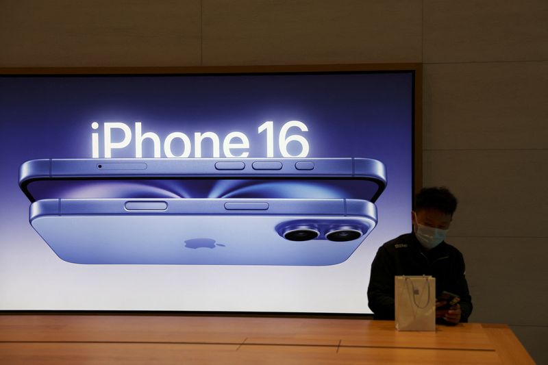 &copy; Reuters. FILE PHOTO: A man sits next to an iPhone 16 advertisement as the new iPhone 16 series smartphones go on sale at an Apple store in Beijing, China September 20, 2024. REUTERS/Florence Lo/File Photo