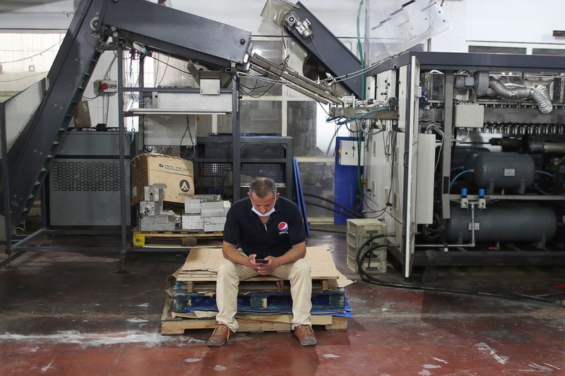 © Reuters. A Palestinian worker uses a mobile phone at Gaza Pepsi factory for soft drinks in Gaza City June 21, 2021. REUTERS/Mohammed Salem/File Photo