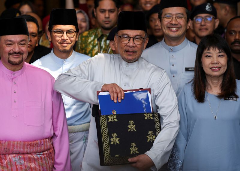 &copy; Reuters. Malaysia's Prime Minister and Finance Minister Anwar Ibrahim holds the 2025 Malaysia budget document at the Finance Ministry building, as he departs to the Parliament, in Putrajaya, Malaysia, October 18, 2024. REUTERS/Hasnoor Hussain