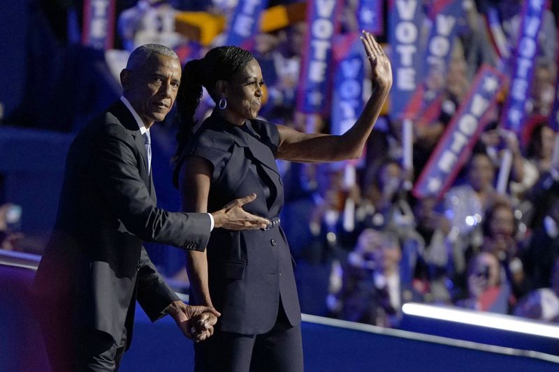 © Reuters. FILE PHOTO: Former U.S. first lady Michelle Obama and her husband, former U.S. President Barack Obama, stand on stage during Day 2 of the Democratic National Convention (DNC) in Chicago, Illinois, U.S., August 20, 2024. REUTERS/Elizabeth Frantz/File Photo