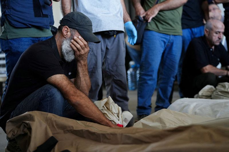 © Reuters. A mourner reacts near the bodies of people who were killed in an Israeli airstrike that destroyed the municipal headquarters in Nabatieh on Wednesday, during a collective funeral held for 13 people in Nabatieh, southern Lebanon, October 18, 2024. REUTERS/Mohammed Yassin