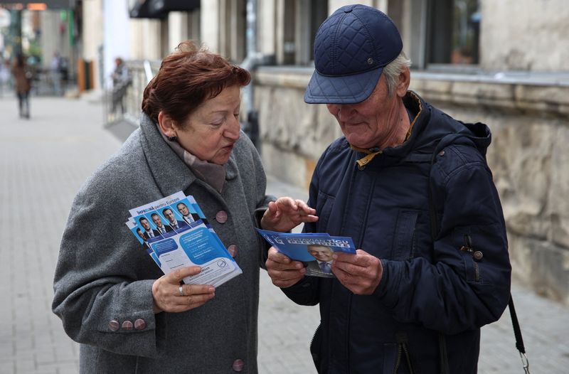 © Reuters. A participant of Moldovan presidential candidate Octavian Ticu's campaign hands out leaflets while agitating voters in a street ahead of the country's upcoming presidential election and a referendum on future European Union membership, in Chisinau, Moldova October 15, 2024. REUTERS/Vladislav Culiomza/File Photo