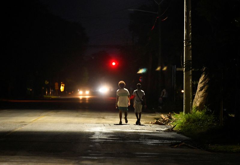 © Reuters. People walk along a street near a street lamp as Cuba's government said on Saturday it had made some progress in gradually re-establishing electrical service across the island, in Havana, Cuba October 19, 2024. REUTERS/Norlys Perez