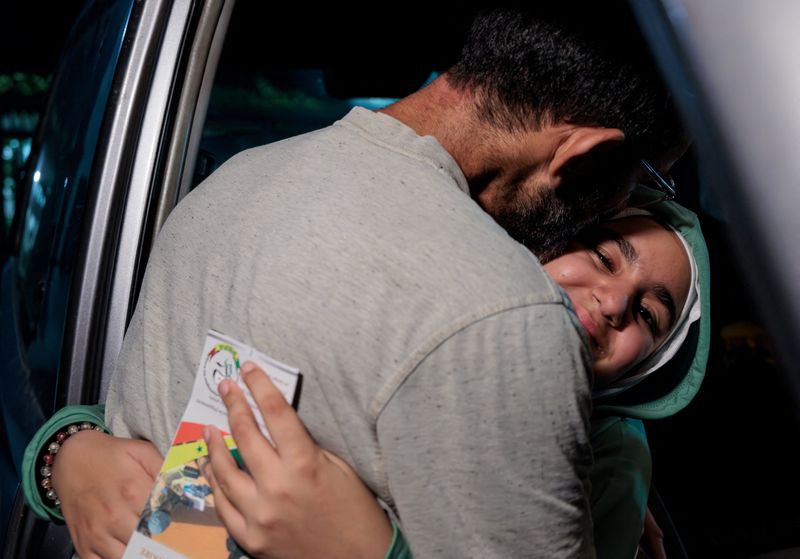 &copy; Reuters. Mariam, 11,  a Lebanese Senegalese girl, is hugged by her father after she arrives on a repatriation flight at Leopold Senghor military airport in Dakar, Senegal  October 19, 2024. Mariam was injured in an Israeli strike that destroyed the house her fathe