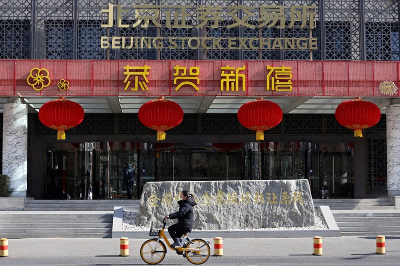 &copy; Reuters. FILE PHOTO: A woman cycles past the Beijing Stock Exchange building adorned with Lunar New Year decorations, on the Financial Street in Beijing, China February 8, 2024. REUTERS/Florence Lo/File Photo