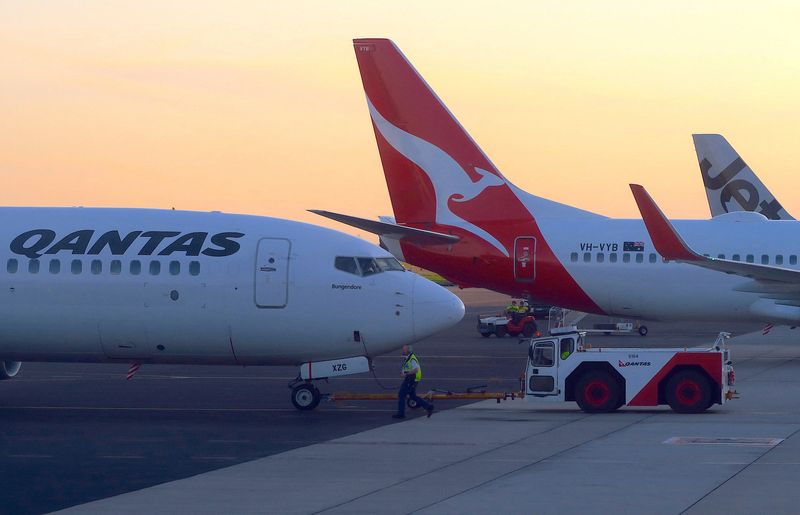 © Reuters. FILE PHOTO: Workers are seen near Qantas Airways, Australia's national carrier, Boeing 737-800 aircraft on the tarmac at Adelaide Airport, Australia, August 22, 2018. REUTERS/David Gray/File Photo