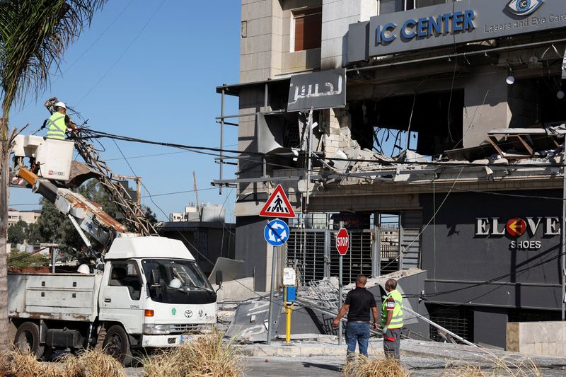 © Reuters. People work at the site of a damaged branch of Al-Qard al-Hassan', a financial institution linked to Lebanon's Hezbollah, in the aftermath of Israeli airstrikes on Sunday that hit several branches of the institution, amid the ongoing hostilities between Hezbollah and Israeli forces, in Beirut suburbs, Lebanon, October 21, 2024. REUTERS/Mohamed Azakir