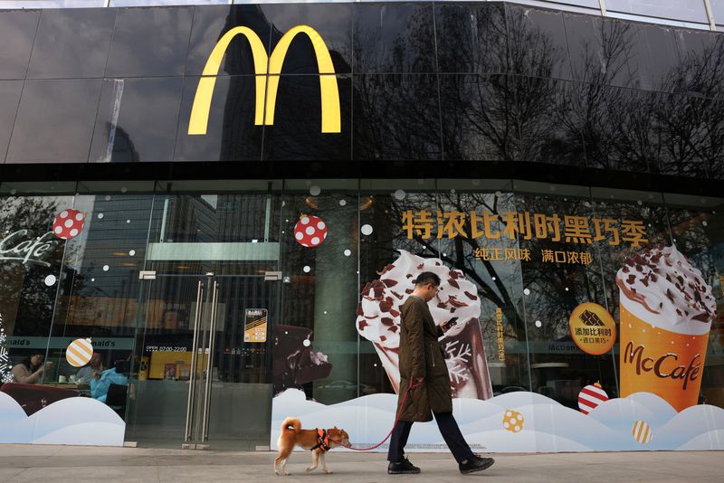 &copy; Reuters. FILE PHOTO: A man walks a dog past a McDonald's restaurant in Beijing, China December 4, 2023. REUTERS/Tingshu Wang/File Photo