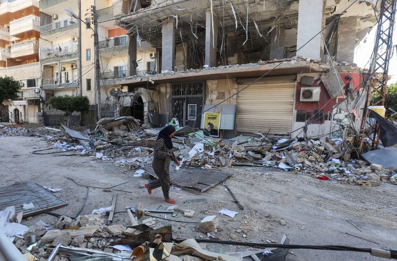 © Reuters. A woman walks past a damaged branch of ‘Al-Qard al-Hassan', in the aftermath of Israeli airstrikes on Sunday that hit several branches of ‘Al-Qard al-Hassan', a financial institution linked to Lebanon's Hezbollah, amid the ongoing hostilities between Hezbollah and Israeli forces, in Tyre, Lebanon, October 21, 2024. REUTERS/Aziz Taher