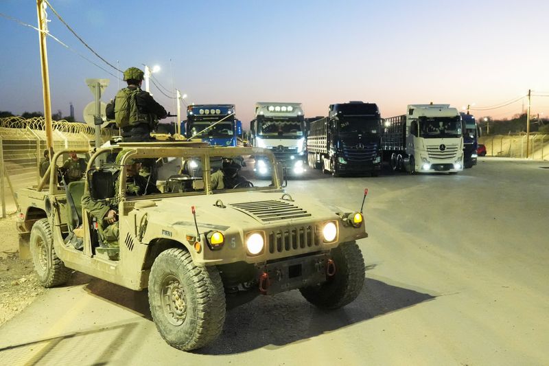 © Reuters. Israeli soldiers sit in a military vehicle near trucks carrying humanitarian aid that wait before making their way to the Gaza Strip, amid the ongoing conflict in Gaza between Israel and Hamas, at Erez Crossing in southern Israel, October 21, 2024. REUTERS/Janis Laizans