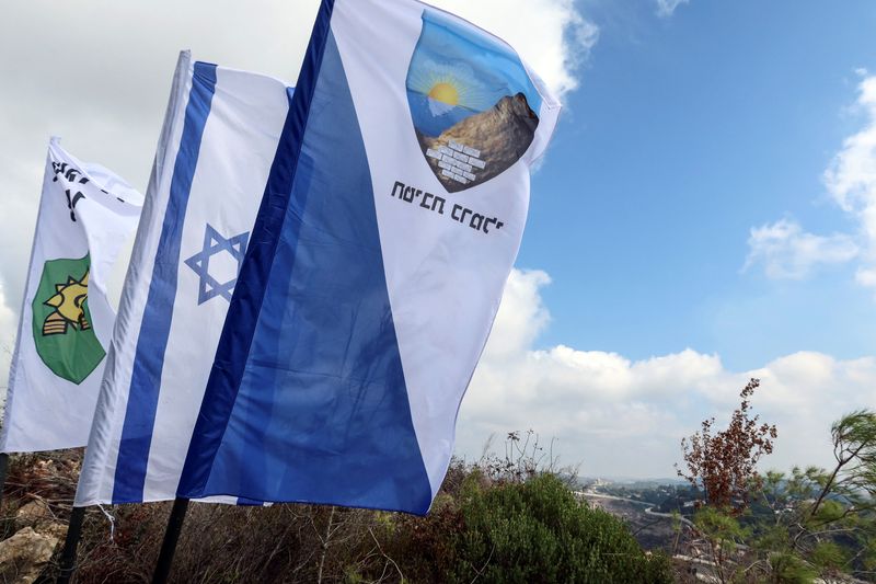 © Reuters. FILE PHOTO: Israeli military insignia and Israel's national flag fly in southern Israel, as part of an incursion during hostilities between Hezbollah and Israel, October 13, 2024. REUTERS/Artorn Pookasook/File Photo