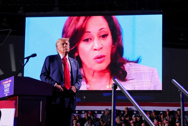 &copy; Reuters. FILE PHOTO: Republican presidential nominee and former U.S. President Donald Trump looks on as Democratic presidential nominee and U.S. Vice President Kamala Harris' face appears as a video plays on a screen, during a rally at Huntington Place in Detroit,