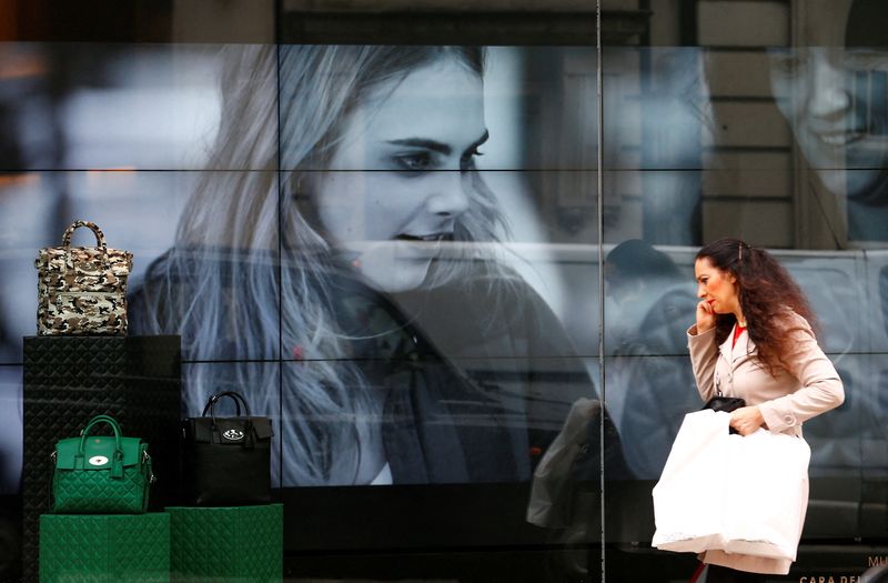 &copy; Reuters. FILE PHOTO: A woman walks past a video display in the shop window of a Mulberry store in central London October 14, 2014. REUTERS/Andrew Winning/File Photo