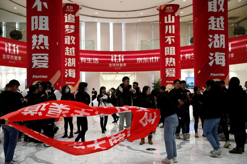 &copy; Reuters. FILE PHOTO: People stand near banners for the Singles’ Day shopping festival at JD.com's headquarters, during an organised tour, in Beijing, China, November 9, 2021. REUTERS/Tingshu Wang/File Photo