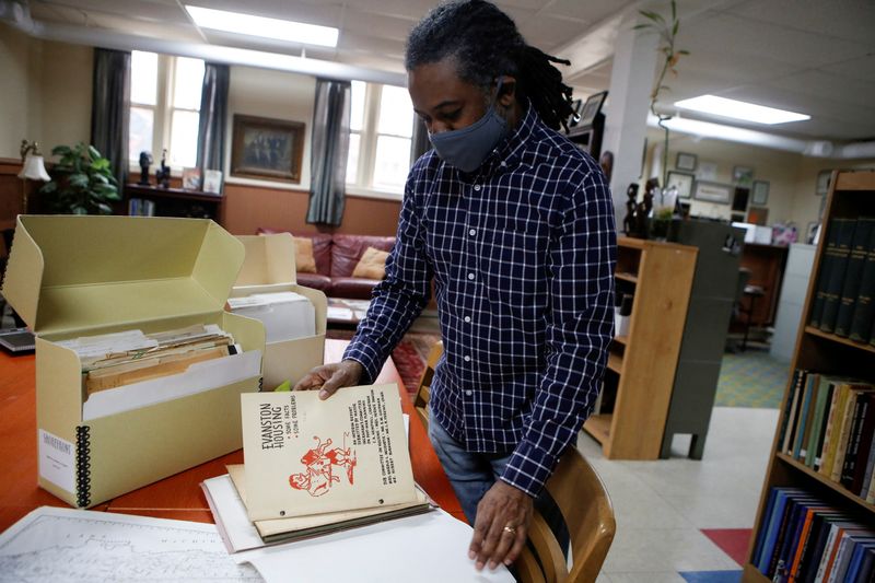 © Reuters. FILE PHOTO: Community historian Morris “Dino” Robinson,  who helped shape the Evanston’s reparations initiative, takes out an old city housing pamphlet at the Shorefront Legacy Center in Evanston, Illinois, U.S., March 17, 2021. REUTERS/Eileen T. Meslar/File Photo