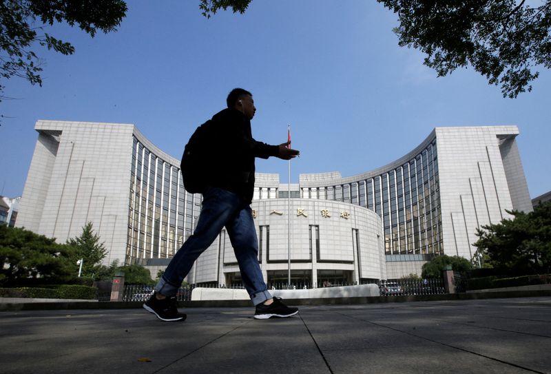 © Reuters. FILE PHOTO: A man walks past the headquarters of the People's Bank of China (PBOC), the central bank, in Beijing, China September 28, 2018. REUTERS/Jason Lee/File Photo