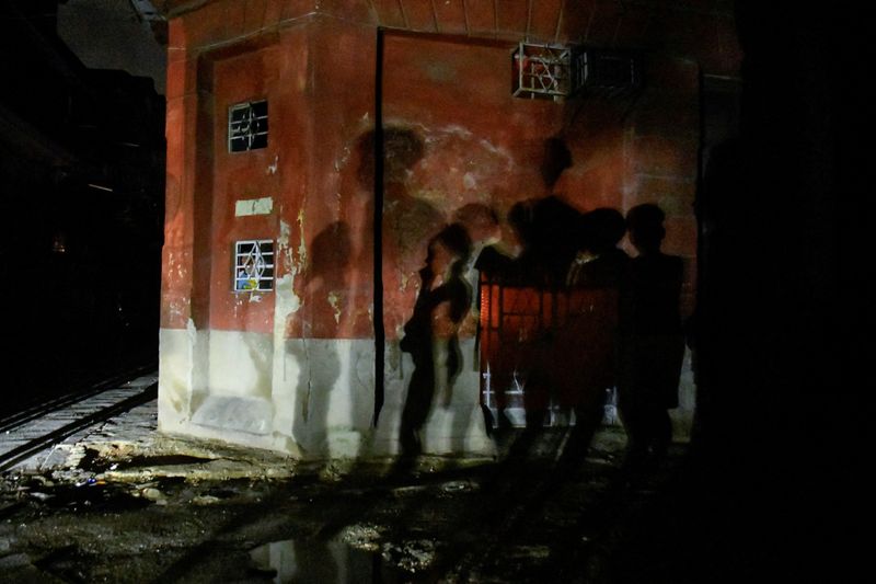 © Reuters. FILE PHOTO: The shadows of people are cast on a wall through the lights of a passing car, as their street remains without electricity while Cuba is making progress restoring power to swaths of the Caribbean island nation, both in Havana and outlying provinces, after the entire national electrical grid crashed last Friday, in Havana, Cuba October 21, 2024. REUTERS/Norlys Perez/File Photo