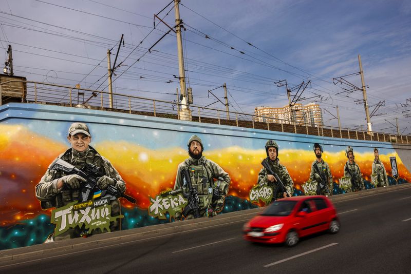 © Reuters. A car drives past murals of fallen Ukrainian soldiers of the Gonor unit of the First Separate Battalion's 