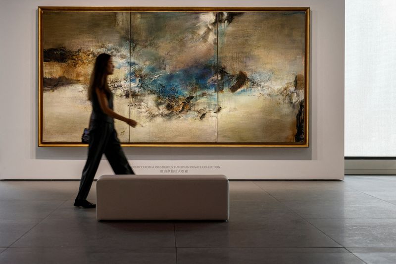 &copy; Reuters. FILE PHOTO: An employee poses for a photo in front of "05.06.80-Triptyque" by artist Zao Wou-Ki during the inaugural sale at Christie's new Asia Pacific headquarters in Hong Kong, China September 19, 2024. REUTERS/Tyrone Siu/File Photo