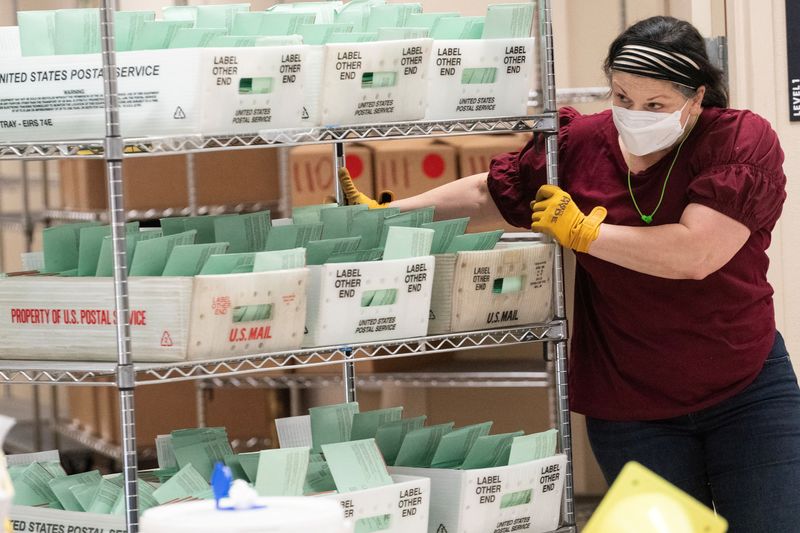 © Reuters. FILE PHOTO: A worker pushes a shelf on wheels to move ballots during a guided tour for the news media at the Maricopa County Tabulation and Election Center (MCTEC) in Phoenix, Arizona, U.S. October 23, 2024.  REUTERS/Go Nakamura/File Photo