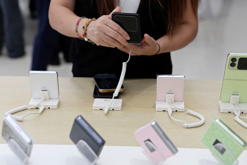 © Reuters. A woman checks a Huawei Nova Flip foldable smartphone displayed at a Huawei flagship store, near an Apple store in Beijing, China September 10, 2024. REUTERS/Florence Lo/File Photo