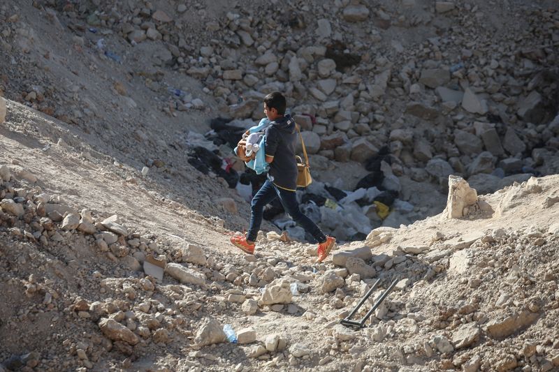 &copy; Reuters. FILE PHOTO: A boy carries and infant, while crossing from Lebanon into Syria on foot, at the Masnaa border crossing, after Israeli strikes earlier this month that Lebanon's transport minister said had closed off the road to vehicles, October 14, 2024. REU