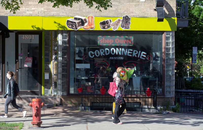 © Reuters. FILE PHOTO: People pass a shop sign written in French, mandated by local laws, in Montreal, Quebec, Canada May 27, 2021. REUTERS/Christinne Muschi/File Photo