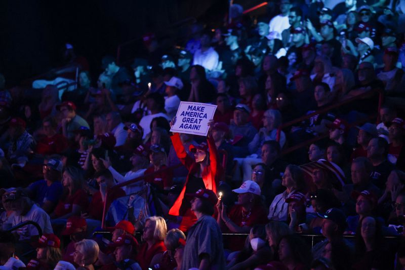 © Reuters. A person among the audience holds up a sign as they attend Republican presidential nominee and former U.S. President Donald Trump's campaign event sponsored by conservative group Turning Point Action, in Las Vegas, Nevada, U.S. October 24, 2024.  REUTERS/Ronda Churchill/File Photo