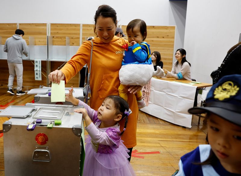 © Reuters. A woman accompanying her children in Halloween costume casts her ballot in the general election at a polling station in Tokyo, Japan October 27, 2024. REUTERS/Kim Kyung-Hoon