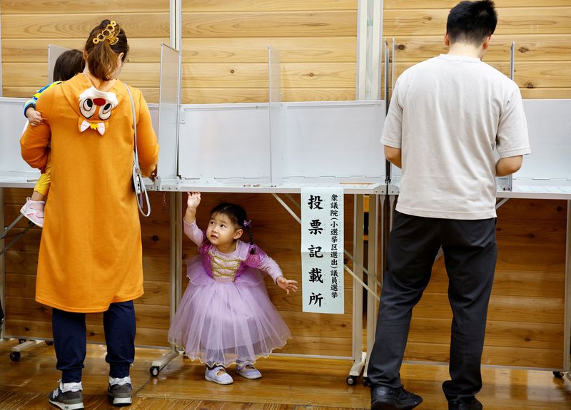 &copy; Reuters. A woman accompanying her children in Halloween costume prepares to vote during the general election at a polling station in Tokyo, Japan October 27, 2024. REUTERS/Kim Kyung-Hoon     