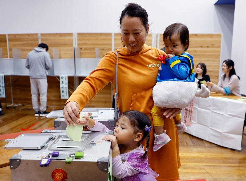 © Reuters. A woman accompanying her children in Halloween costume casts her ballot in the general election at a polling station in Tokyo, Japan October 27, 2024. REUTERS/Kim Kyung-Hoon