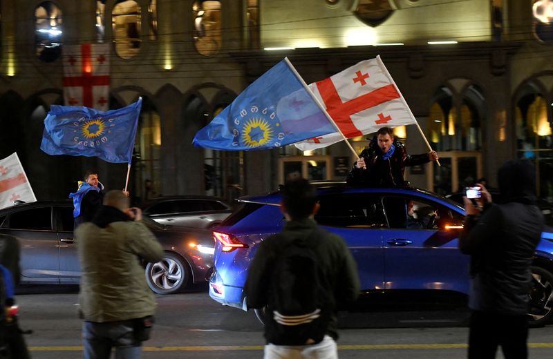 © Reuters. Supporters of the Georgian Dream party wave Georgian flags and the party's flags from cars after the announcement of exit poll results in parliamentary elections, in Tbilisi, Georgia October 26, 2024. REUTERS/Zurab Javakhadze/File Photo