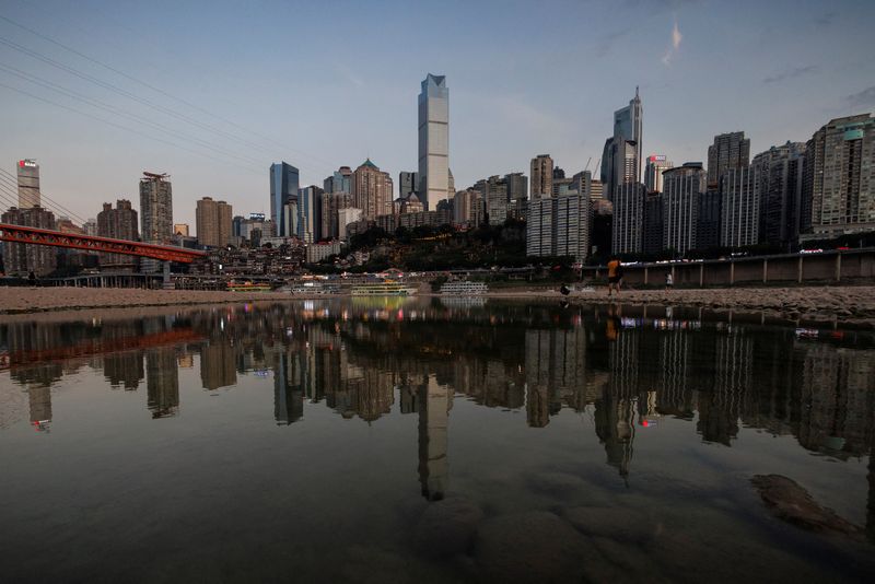 © Reuters. FILE PHOTO: The city skyline is reflected in a pool left on the dry riverbed of the receding Jialing river, China, August 20, 2022. REUTERS/Thomas Peter/File Photo