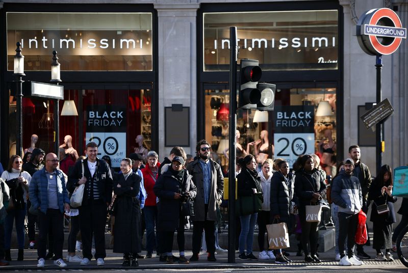 © Reuters. FILE PHOTO: People stand near Black Friday signage in shop windows during Black Friday on Oxford Street in London, Britain, November 25, 2022. REUTERS/Henry Nicholls/File Photo