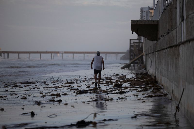 &copy; Reuters. FILE PHOTO: A man walks on the beach after Hurricane Milton made landfall in South Daytona, Florida, U.S., October 11, 2024. REUTERS/Ricardo Arduengo/File Photo