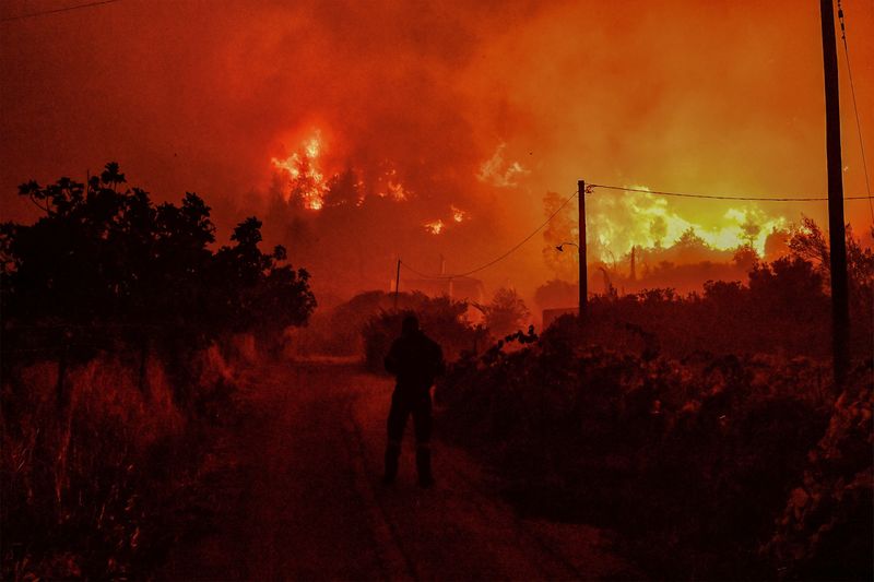 &copy; Reuters. FILE PHOTO: A man walks on a dirt road as a wildfire burns next to the village of Ano Loutro, near Corinth, Greece, September 30, 2024. REUTERS/Vassilis Psomas/File Photo