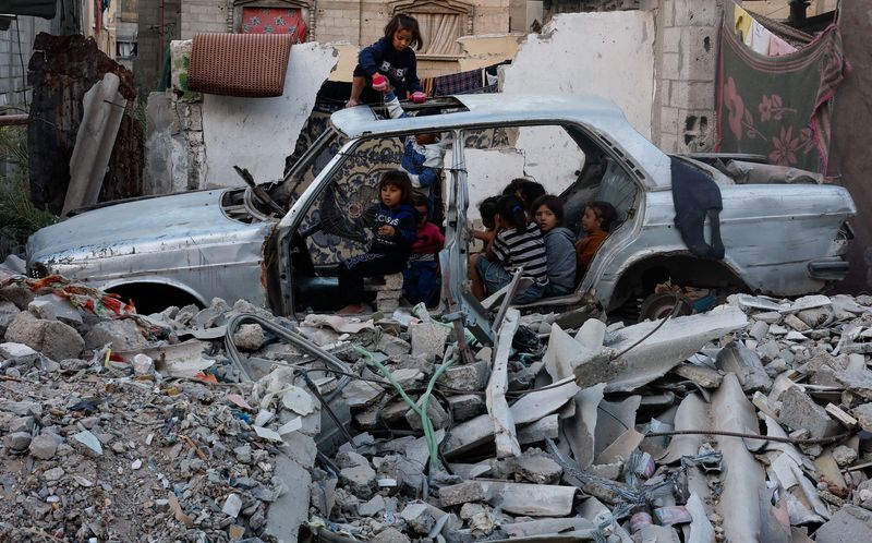 © Reuters. Palestinian children gather at a destroyed vehicle, amid the Israel-Hamas conflict, in Khan Younis, in the southern Gaza Strip, October 27, 2024. REUTERS/Mohammed Salem