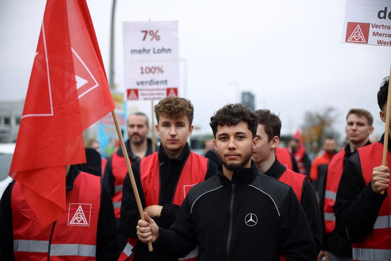 © Reuters. A protester holds a flag with the logo of the union IG Metall during a protest rally by employees of German car maker Mercedes demanding higher wages, at a Mercedes plant in Berlin, Germany, October 29, 2024.   REUTERS/Liesa Johannssen