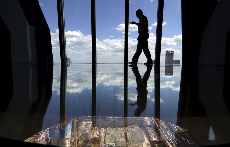 © Reuters. FILE PHOTO: A man walks on the glass floor area constructed as a view point next to a construction site in Beijing's central business district, June 11, 2015. REUTERS/Jason Lee/File Photo