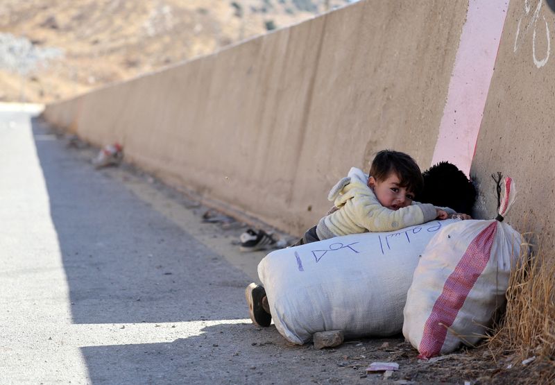 © Reuters. A child holds onto their belongings while crossing from Lebanon into Syria, as people flee the ongoing hostilities between Hezbollah and Israeli forces, at Masnaa border crossing, Lebanon October 28, 2024. REUTERS/Mohamed Abd El Ghany     