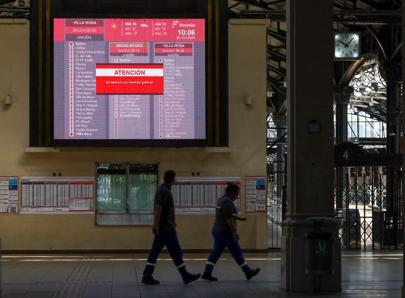 &copy; Reuters. Workers walk inside Retiro train station under a screen that reads "Attention, no service because of union's measures" during a 24-hour general strike called by transport unions against Argentina's President Javier Milei government's adjustment policy, in