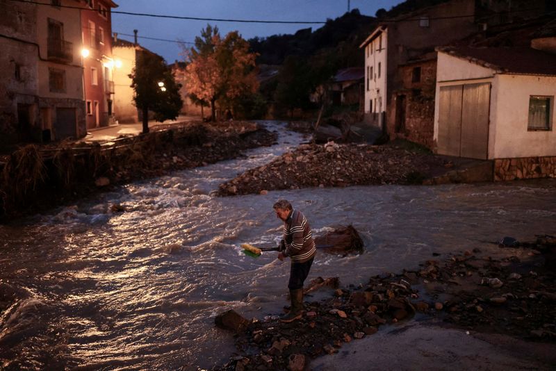 © Reuters. Miguel, 69, washes his sweeping brooms in the Dry River (Rio Seco) after cleaning his house, amid flooding caused by heavy rains, in La Hoz de la Vieja, Teruel province, Spain October 30, 2024. REUTERS/Nacho Doce