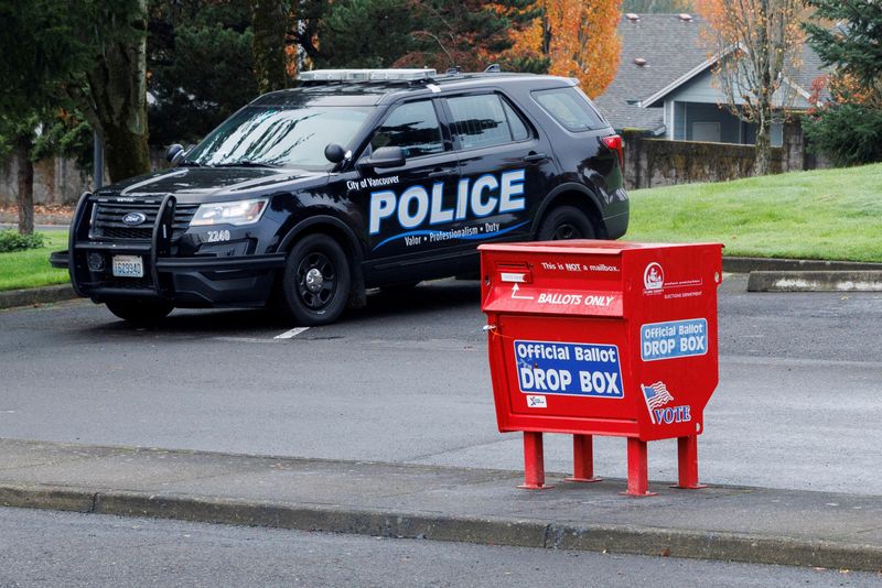 &copy; Reuters. Officer Tyler Knott of the Vancouver Police Department surveils ballot boxes, where a freshly replaced ballot box stands in the Fisher's Landing Transit Center, following what police believe were three arsons at ballot drop boxes in the northwestern U.S. 