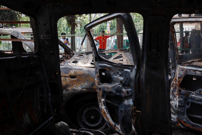 © Reuters. FILE PHOTO: People stand near vandalised cars at the Mohammadpur Police Station, after the resignation of Bangladeshi Prime Minister Sheikh Hasina, in Dhaka, Bangladesh, August 6, 2024. REUTERS/Mohammad Ponir Hossain/File Photo