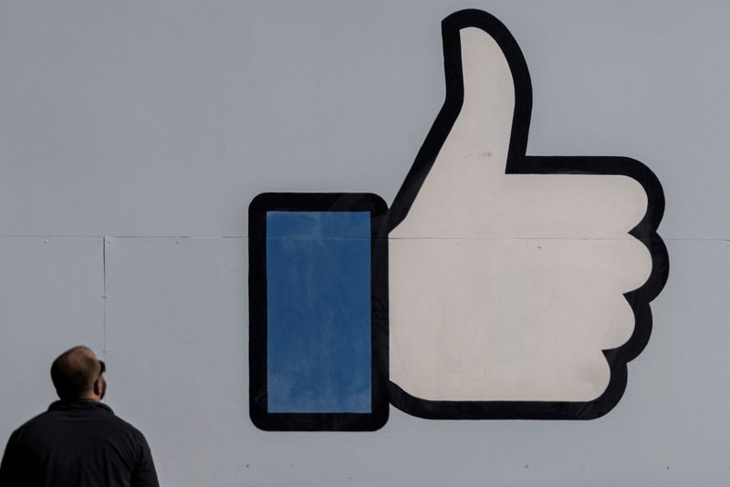 © Reuters. A man stands in front of the entrance sign to Facebook headquarters in Menlo Park, California, U.S. October 27, 2021.  REUTERS/Carlos Barria/File Photo