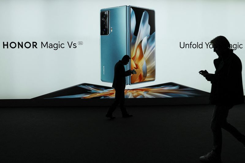 ©Reuters. People walk near the Honor Magic vs Phone billboard during the GSMA's 2023 Mobile World Congress (MWC) in Barcelona, ​​Spain on March 1, 2023. Reuters/Nacho Doce/File photo