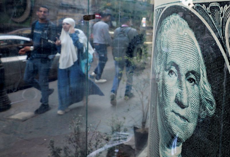 © Reuters. FILE PHOTO: People walk past a currency exchange point, displaying an image of the U.S. dollar, in Cairo, Egypt, March 6, 2024. REUTERS/Mohamed Abd El Ghany/File Photo